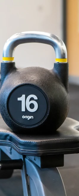 16kg kettlebell on a padded bench in the college gym's strength training area. 16kg kettlebell on a padded bench in the college gym's strength training area.